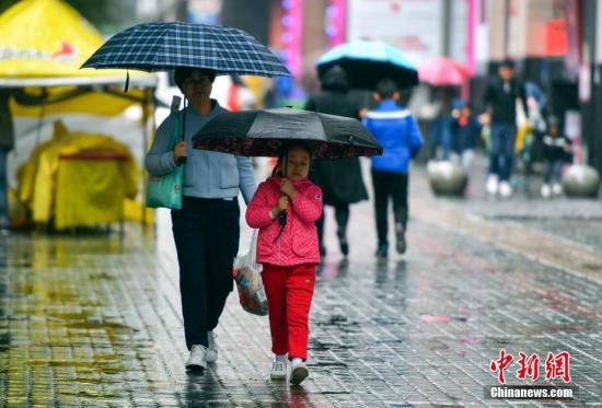 資料圖：9月24日，新疆烏魯木齊市降下秋雨，外出民眾打著雨傘快步前行。 <a target='_blank' href='http://www.chinanews.com/'>中新社</a>記者 劉新 攝