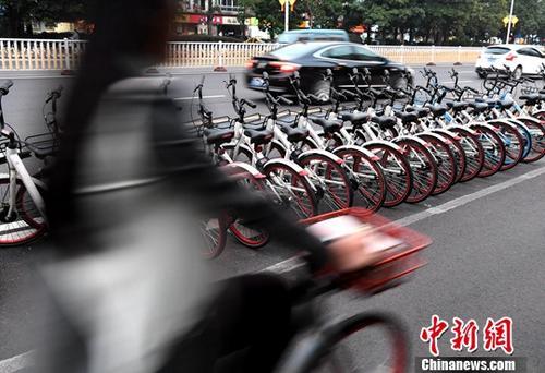 資料圖：路人騎著共享單車經(jīng)過(guò)“車堆”。<a target='_blank' href='http://www.chinanews.com/'>中新社</a>記者 張斌 攝